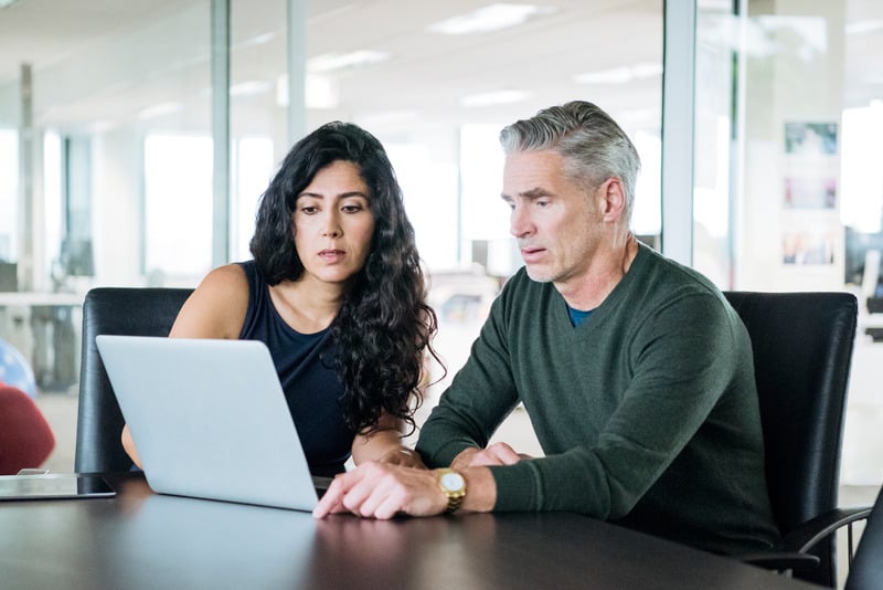 Colleagues discussing work around a shared laptop